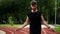 Cropped shot of muscular man standing on running track outdoors on modern stadium doing exercise with skipping rope