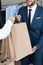 cropped shot of seller giving shopping bags to smiling businessman