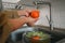 Cropped shot senior housewife washing vegetables in kitchen sink before cooking healthy food