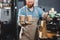 cropped shot of smiling bearded barista holding disposable coffee cups and paper bag