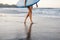 cropped shot of sportswoman in swimming suit with blue surfing board walking