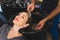 Cropped shot of unrecognizable hairdresser washing blond hair of his positive smiling female client in beauty salon.