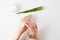 cropped shot of woman applying organic cream on hands, aloe vera leaf and cream container on white surface