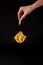 cropped shot of woman folding french fry poured into ketchup over box of fries isolated on black