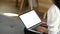 Cropped shot of woman freelancer hands typing on laptop with white screen.