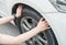 Cropped shot of woman hands touching and checking her car tyre. She worrying about somethings wrong with her wheel.