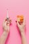 cropped shot of woman holding plastic container with various sorted pills and electric thermometer