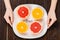 cropped shot of woman holding plate with halved citrus fruits and diet inscription