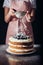 cropped shot of woman spilling sugar powder onto tasty blackberry