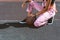 Cropped shot of woman in sports bra and pink overalls sitting at ground of sports field