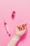 cropped shot of womans hand lying on pink surface with syringe and bottle with love