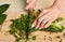 Cropped shot of womans hands chopping scallions and parsley on wooden board
