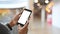 Cropped shot of young businessman holding crop black smartphone with white blank screen on hands.