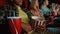 Cropped shot of young people having drinks and popcorn basket while watching movie in cinema auditorium