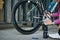 Cropped shot of young woman, professional female cyclist holding pump for inflating the tire of her bicycle, kneeling