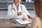 Cropped smiling millennial indian female doctor in white coat take money from client in clinic office