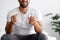 Cropped smiling millennial muscular european male with glass of water and pill in white bedroom interior