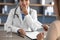 Cropped smiling young indian woman doctor in white coat with stethoscope takes money from patient