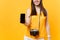 Cropped tourist woman holding mobile smart phone with blank black empty screen isolated on yellow orange background