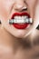 cropped view of angry woman with red lips holding dollar banknote in teeth