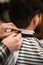 cropped view of barber fixing hairdressing collar around neck of man client.