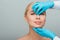 Cropped view of beautician in latex gloves touching nose of happy naked woman