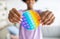 Cropped view of black teenager holding POP IT toy in outstretched hands at home, closeup