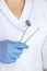 Cropped view of dentist in latex glove holding Dentist Professional tool near dental set blurred on of doctors coat uniform