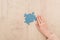 Cropped view of female hand near blue puzzles on wooden table.