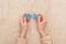 Cropped view of female hands holding blue puzzles on wooden table.