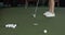 Cropped view of golf ball hitting in hale in synthetic grass