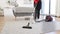 Cropped view of hands of woman cleaning service worker vacuuming carpet.