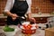 Cropped view. Housewife in black chef& x27;s apron holding wooden teaspoon with sugar while preparing pickles in home