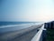 Cropped view of a lonely blue sea and beach and partial balcony wall on daytime.