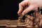 Cropped view of man doing move with knight on wooden chessboard isolated on black.