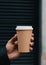 cropped view of man holding paper cup of coffee in hand on black background Generative AI