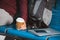 Cropped view of man holding paper cup near backpack laptop and passport