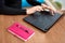 Cropped view of office worker sitting at table in cafe. Female hands type long text on keypad on laptop