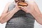 Cropped view of overweight man holding delicious burger