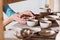 cropped view of potter with ceramic bowls on shelves