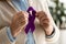 cropped view of retired woman holding purple ribbon at home.
