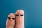 cropped view of smiling fingers in sunglasses isolated on blue.