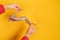 Cropped view of stylish golden shoe in female hands with perfect red manicure. Yellow studio background with copy space.