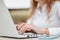 Cropped view of successful female entrepreneur sits in front of opened laptop computer, works on financial report, keyboards infor