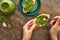 Cropped view of woman adding pesto sauce with spoon on baguette slice on stone surface