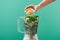 Cropped view of woman adding pine nuts to basil leaves in food processor isolated on green