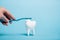 Cropped view of woman brushing white tooth model with toothbrush and toothpaste on blue background.