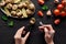 Cropped view of woman eating delicious escargots with lemon on black wooden table.