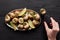 Cropped view of woman eating delicious escargots with lemon on black wooden table.