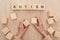 Cropped view of woman holding empty wooden cubes near autism lettering.